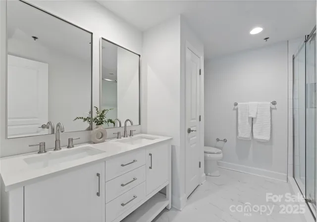 a bathroom with a double vanity sink toilet mirror and shower