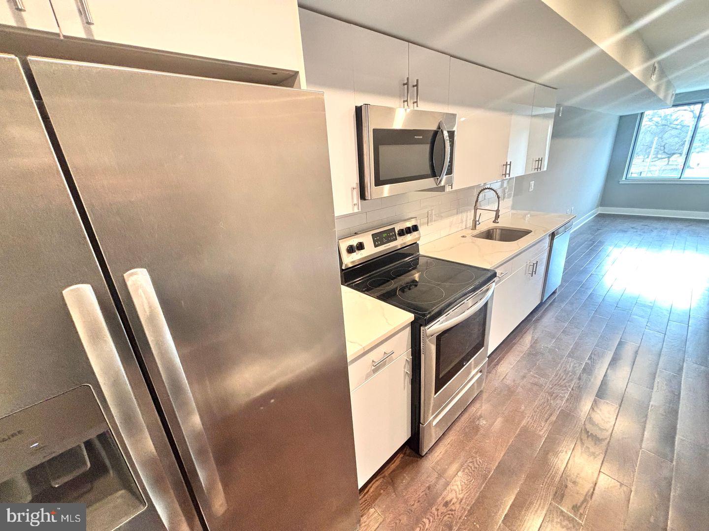 a kitchen with stainless steel appliances a refrigerator a sink a stove a microwave oven a sink and dishwasher