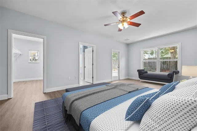 an empty room with wooden floor chandelier fan and windows