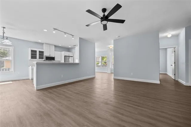 an empty room with wooden floor chandelier and windows