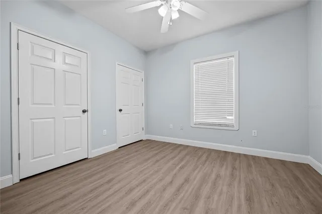 a view of an empty room with window and wooden floor