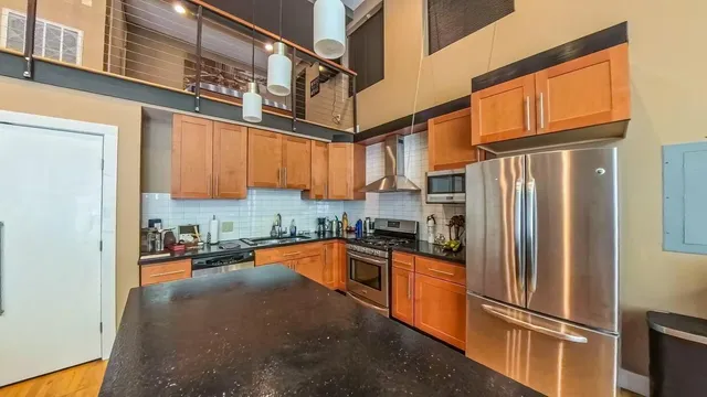 a kitchen with stainless steel appliances granite countertop a refrigerator a stove and a sink with wooden floor