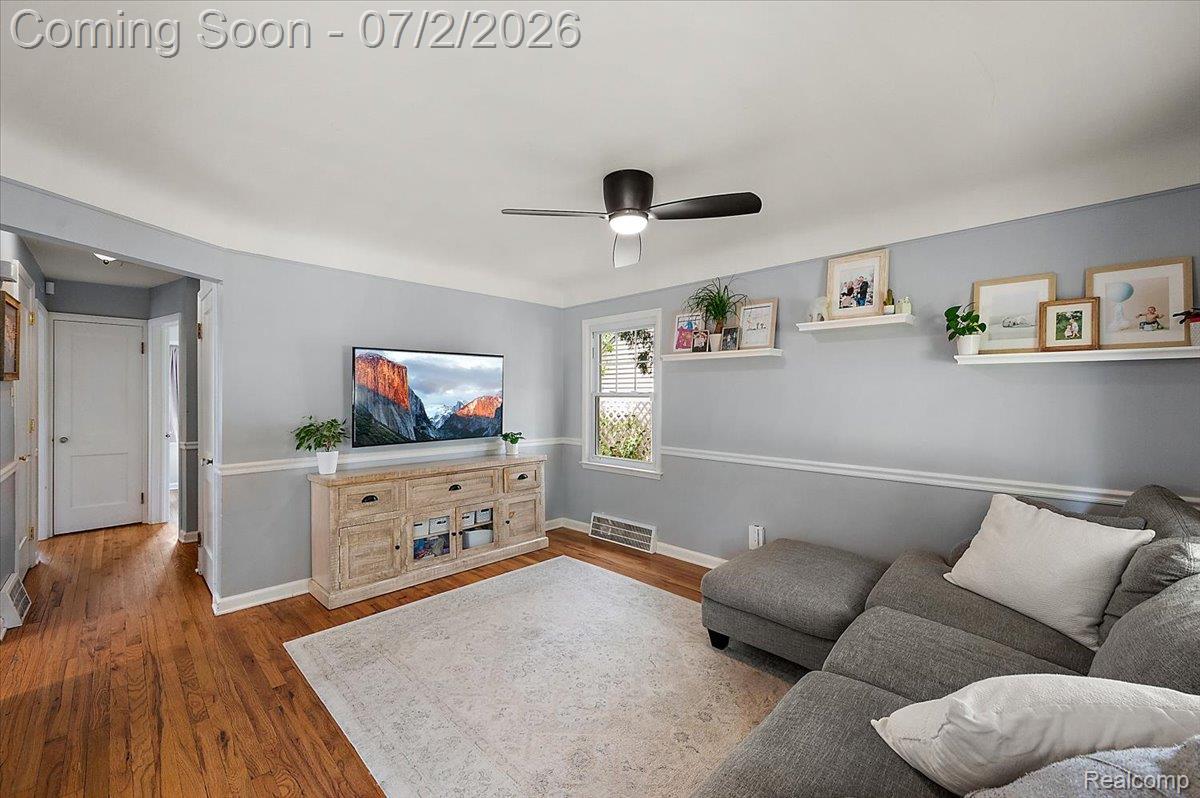 1706 Princeton Road Berkley, MI 48072 - Photo 6 of 49 Living area featuring hardwood flooring, a ceiling fan, light blue walls with white chair rail molding, and a white trim window