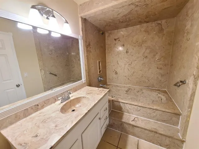a bathroom with a sink vanity granite tub and shower