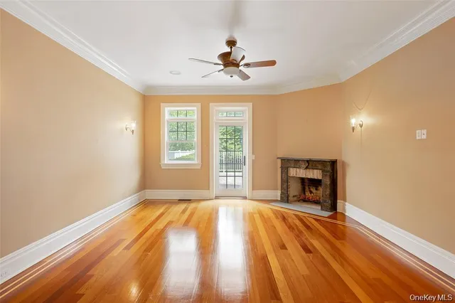 a view of empty room with wooden floor fireplace and a window