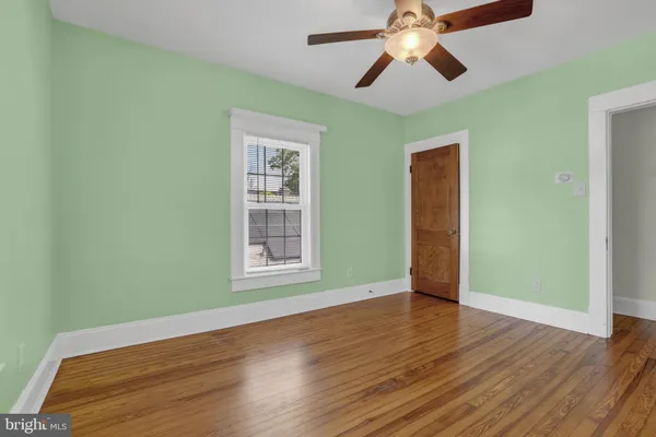 an empty room with wooden floor chandelier fan and windows
