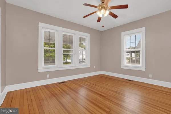 a view of an empty room with window and wooden floor