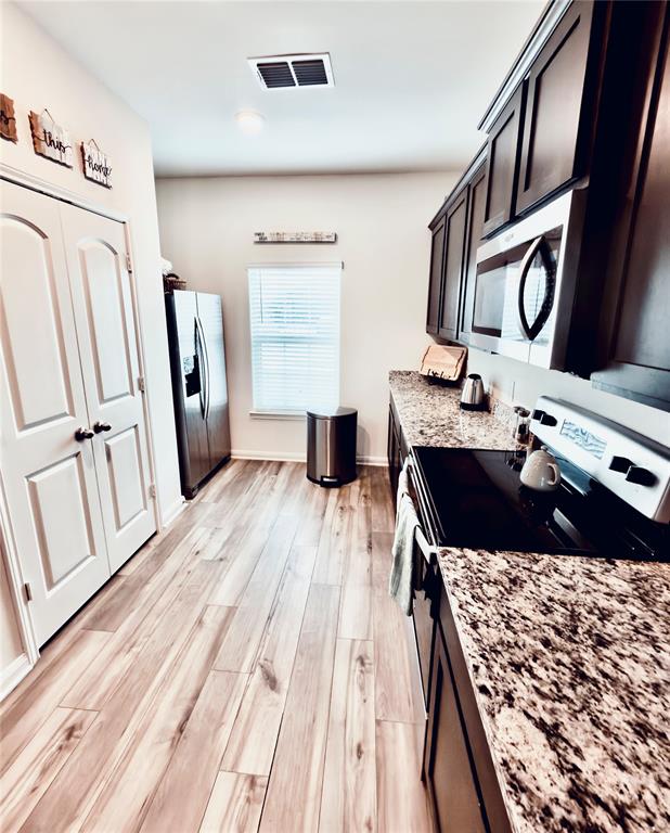 196 Cattlemans Crk Road West Newark, TX 76071 - Photo 2 of 31 Kitchen featuring wood-finish flooring, dark cabinetry, and speckled countertops