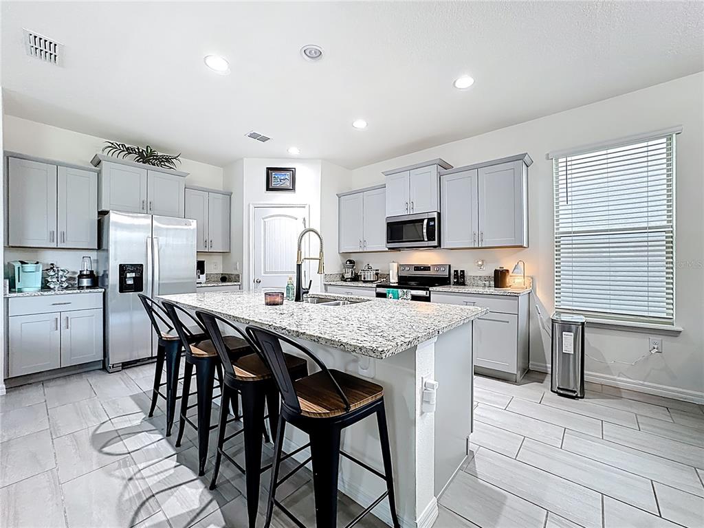 16632 Point Rock Drive Winter Garden, FL 34787 - Photo 11 of 74 a kitchen with stainless steel appliances kitchen island granite countertop a table chairs sink refrigerator and cabinets