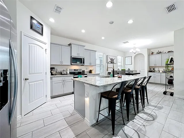 a kitchen with stainless steel appliances kitchen island granite countertop a sink and a stove top oven with white cabinets