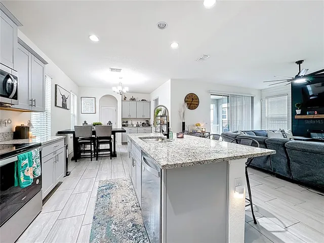 a kitchen with granite countertop kitchen island stainless steel appliances a sink and a refrigerator