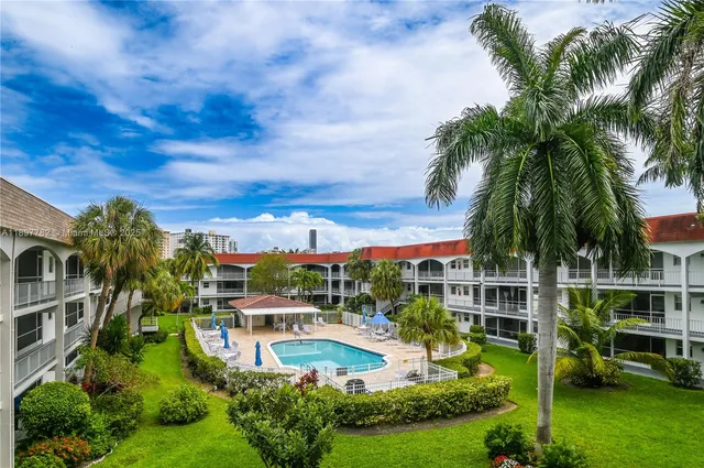 a palm tree sitting in front of a house with a garden