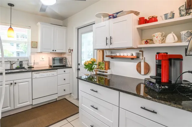 a kitchen with granite countertop white cabinets and white appliances