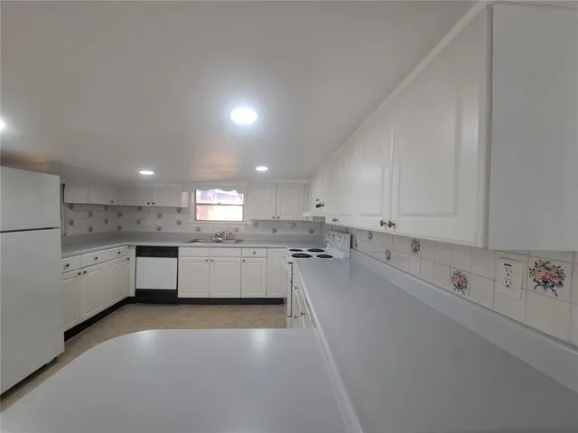 a large white kitchen with lots of counter space white cabinets and stainless steel appliances