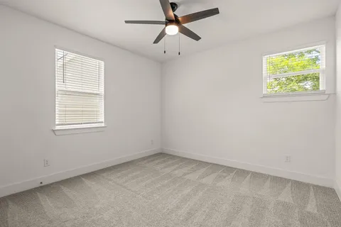 an empty room with windows and ceiling fan