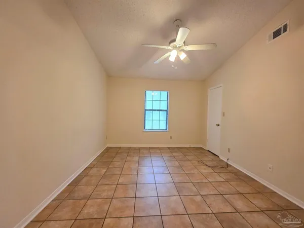 a view of an empty room with window and chandelier fan