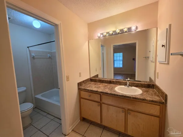 a bathroom with a granite countertop sink toilet mirror and bathtub