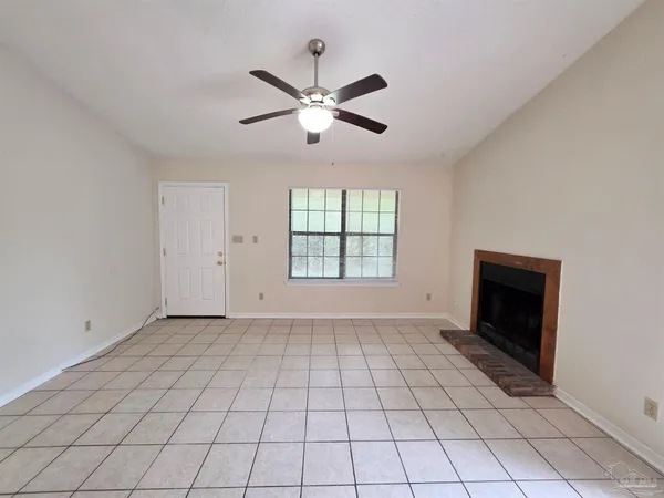 a view of an empty room with window and chandelier fan