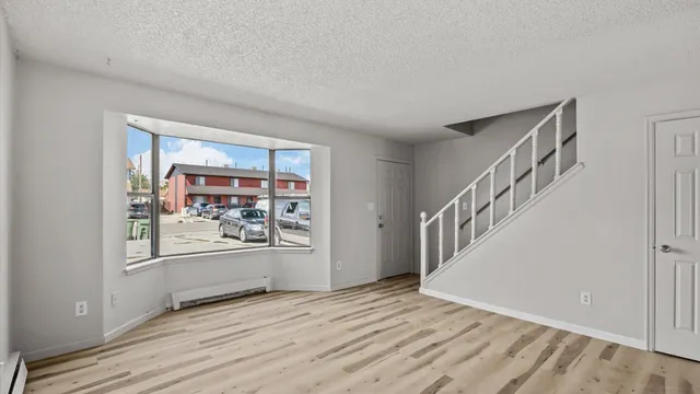 a view of an empty room with window and wooden floor