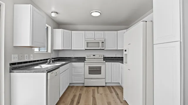 a kitchen with stainless steel appliances granite countertop a stove a sink and white cabinets