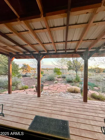 a view of a patio with lawn chairs under wooden roof with potted plants