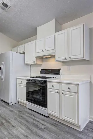 a kitchen with granite countertop white cabinets and stainless steel appliances