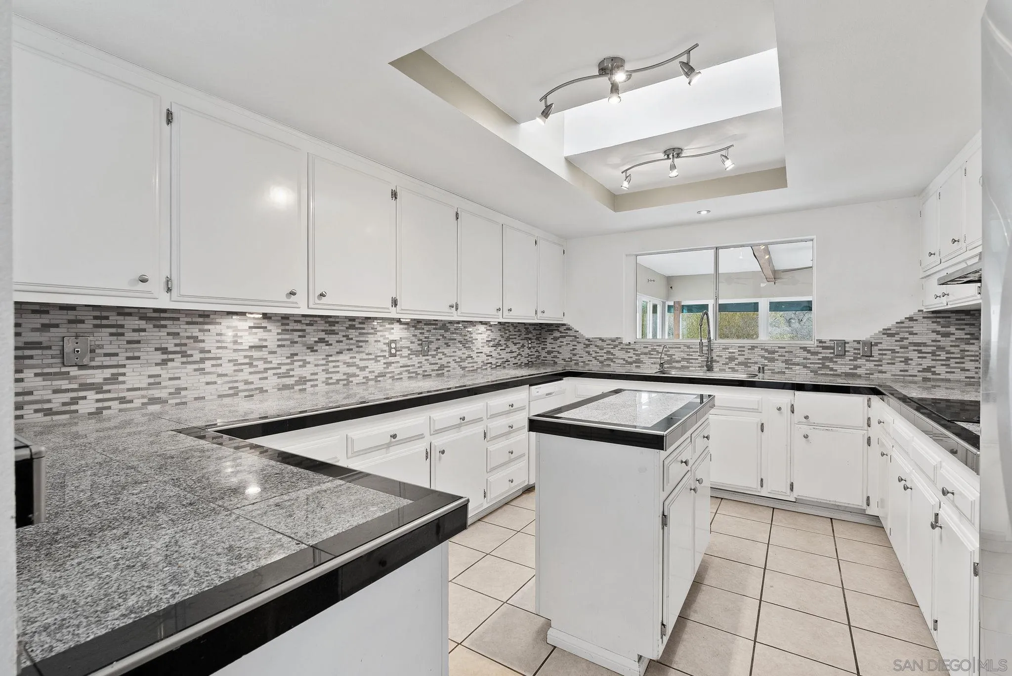 31162 Old River Road Bonsall, CA 92003 - Photo 32 of 44 a kitchen with granite countertop white cabinets and white appliances
