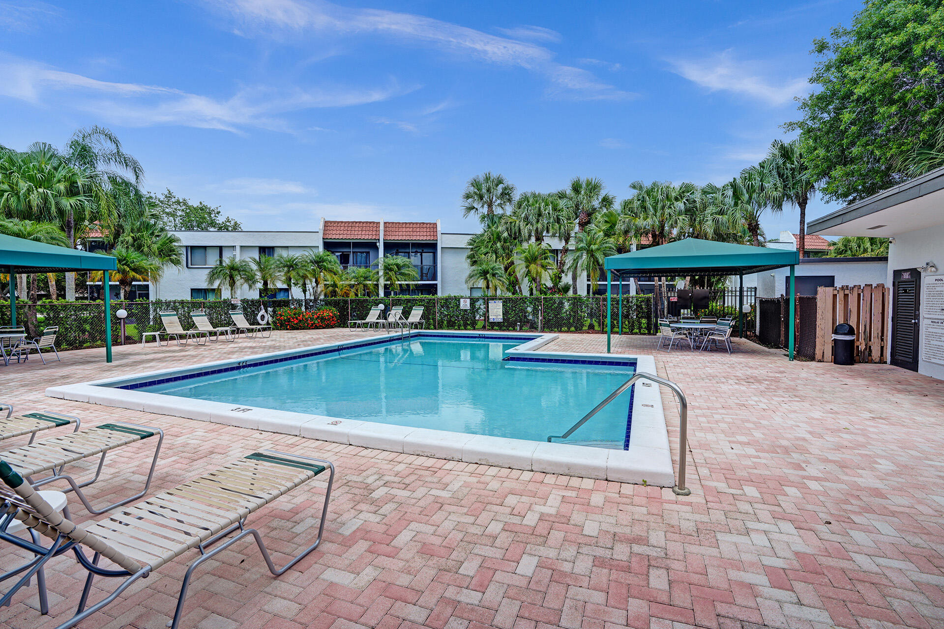 300 Racquet Club Road, Unit 103 Weston, FL 33326 - Photo 31 of 31 a view of a swimming pool with a table and chairs under an umbrella