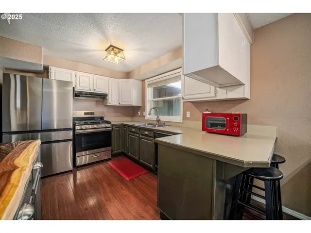 a kitchen with a refrigerator a stove a sink dishwasher and a dining table with wooden floor