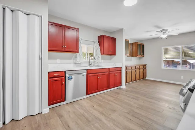 a kitchen with stainless steel appliances granite countertop a sink dishwasher stove top oven and cabinets with wooden floor