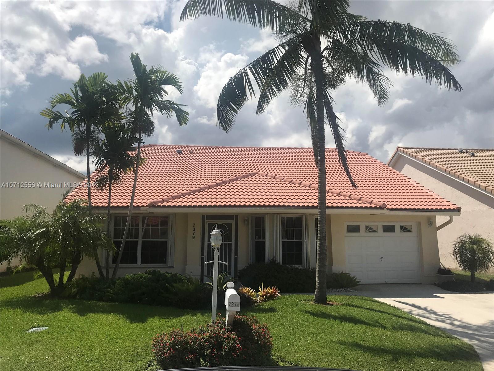 7379 Shell Ridge Terrace Lake Worth, FL 33467 - Photo 3 of 22 a front view of a house with a garden and trees