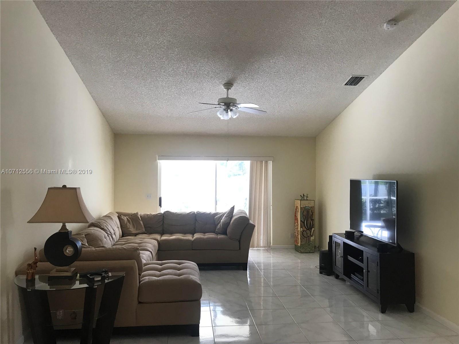 7379 Shell Ridge Terrace Lake Worth, FL 33467 - Photo 10 of 22 a living room with furniture a flat screen tv and a window