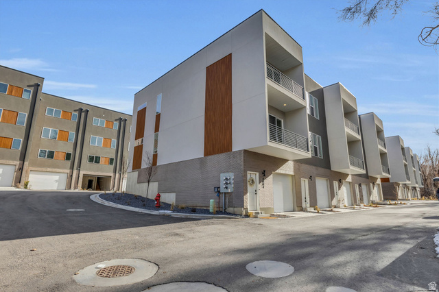 4016 South Burch Way Ogden, UT 84405 - Photo 24 of 30 Contemporary multi-level townhome featuring a minimalist exterior design with white stucco, wood-look accents, and gray brickwork
