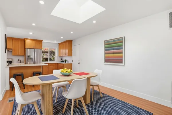 a kitchen with a refrigerator a stove a sink cabinets and a dining table