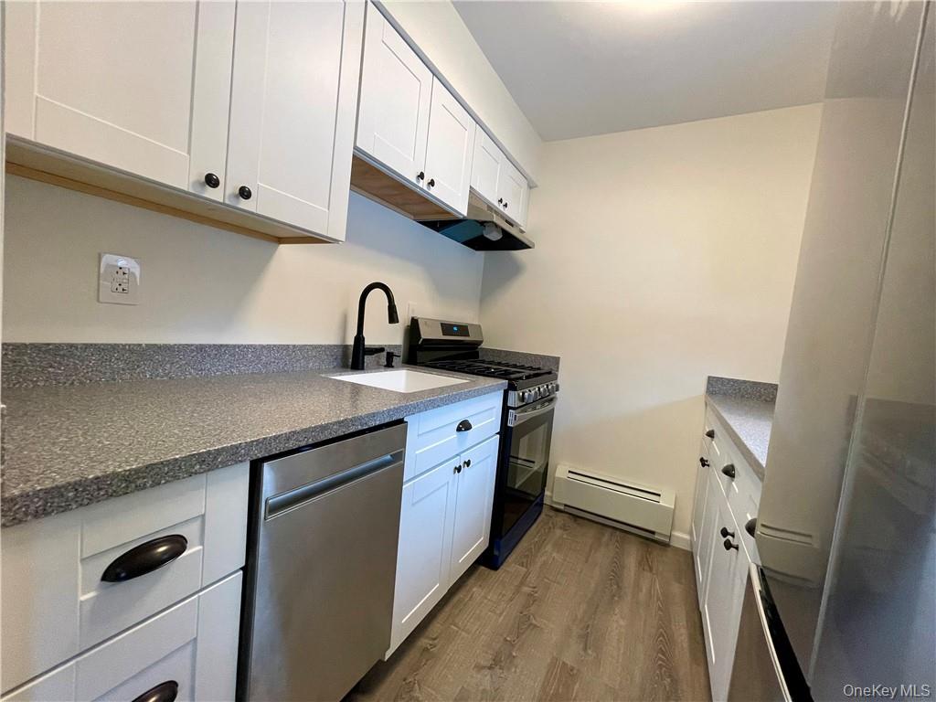 27 Tanager Road, Unit 2702 Monroe, NY 10950 - Photo 2 of 17 Modern kitchen featuring white shaker cabinetry with dark hardware, speckled countertops, a stainless steel dishwasher, and a gas range