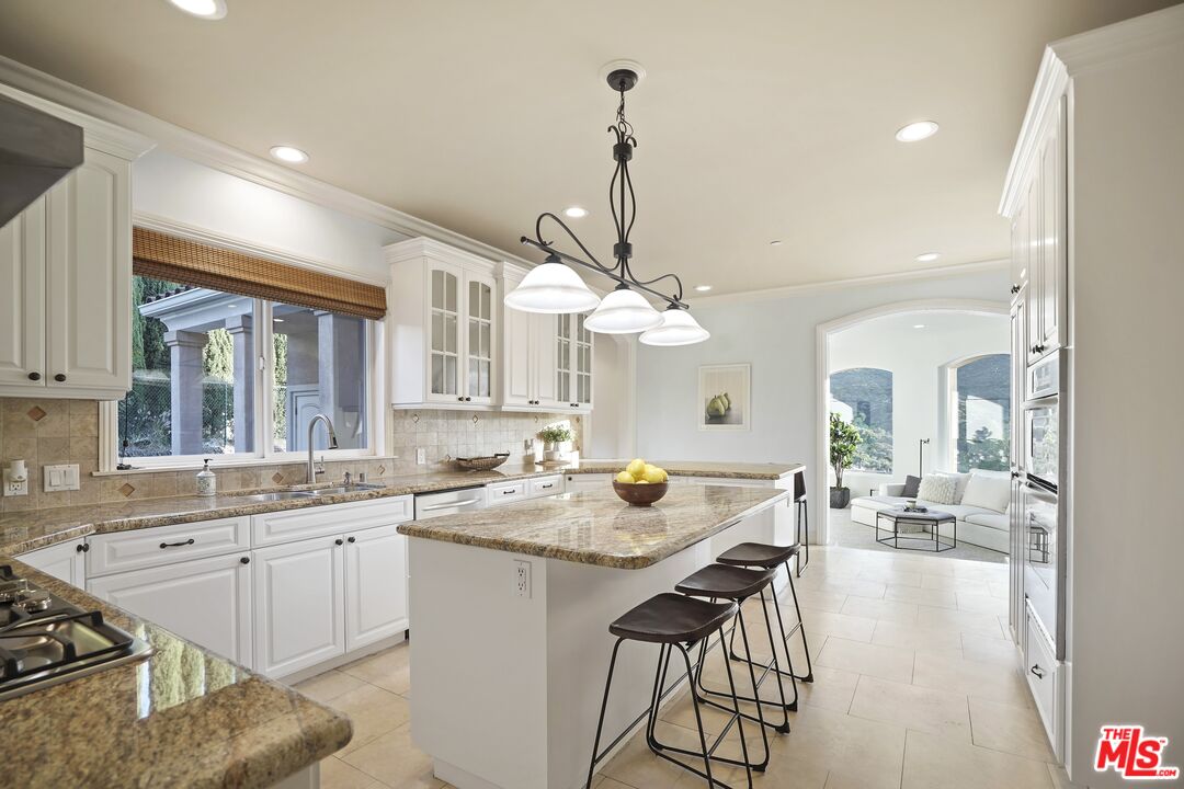 969 Crown Hill Drive Simi Valley, CA 93063 - Photo 16 of 62 a kitchen with a dining table chairs sink and cabinets