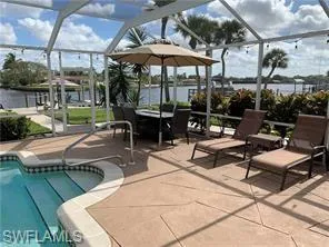 a view of a patio with table and chairs under an umbrella with a barbeque grill and plants