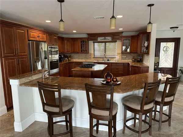 a kitchen with stainless steel appliances granite countertop a stove a refrigerator a kitchen island a table and chairs
