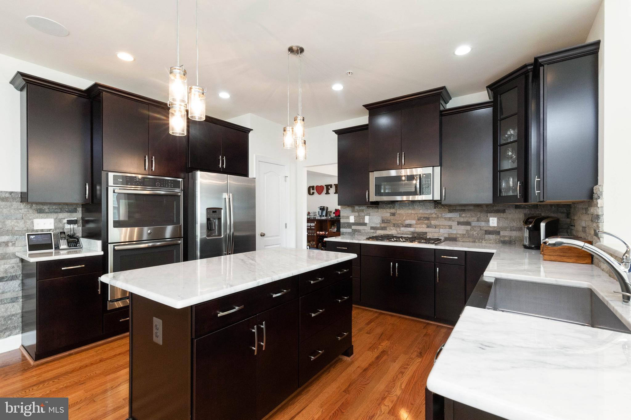 a large kitchen with stainless steel appliances kitchen island granite countertop a stove refrigerator and cabinets