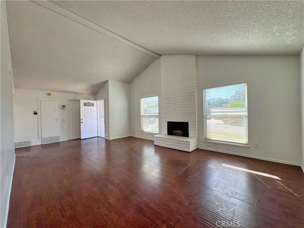 22574 Kentfield Street Grand Terrace, CA 92313 - Photo 4 of 22 an empty room with wooden floor fireplace and windows