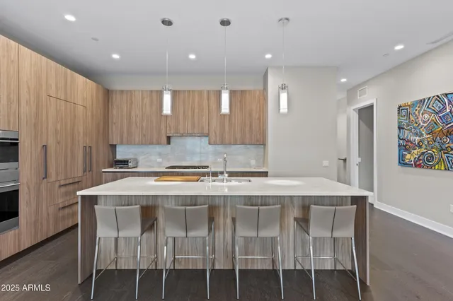 a kitchen with stainless steel appliances granite countertop a table chairs sink and cabinets