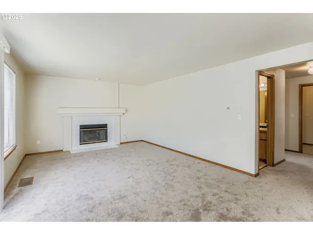 an empty room with windows and chandelier fan
