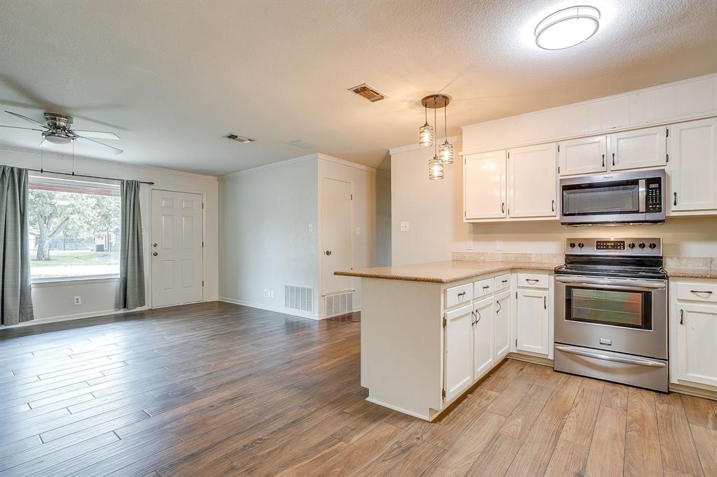 709 North Ave B Springtown, TX 76082 - Photo 13 of 32 a kitchen with granite countertop a stove cabinets and wooden floor
