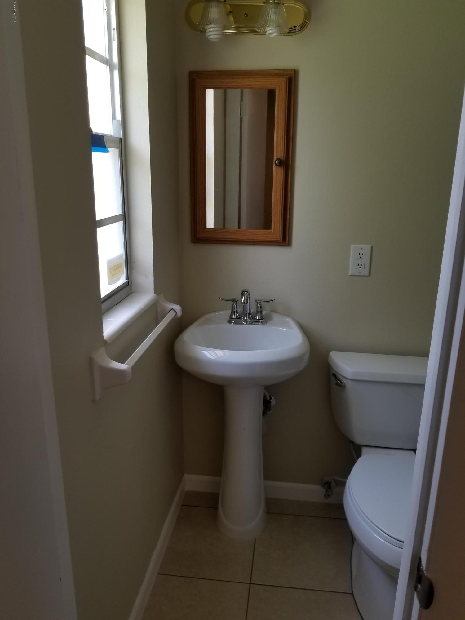 2793 Breeze Ridge Road Melbourne, FL 32935 - Photo 11 of 15 a bathroom with a toilet sink and mirror