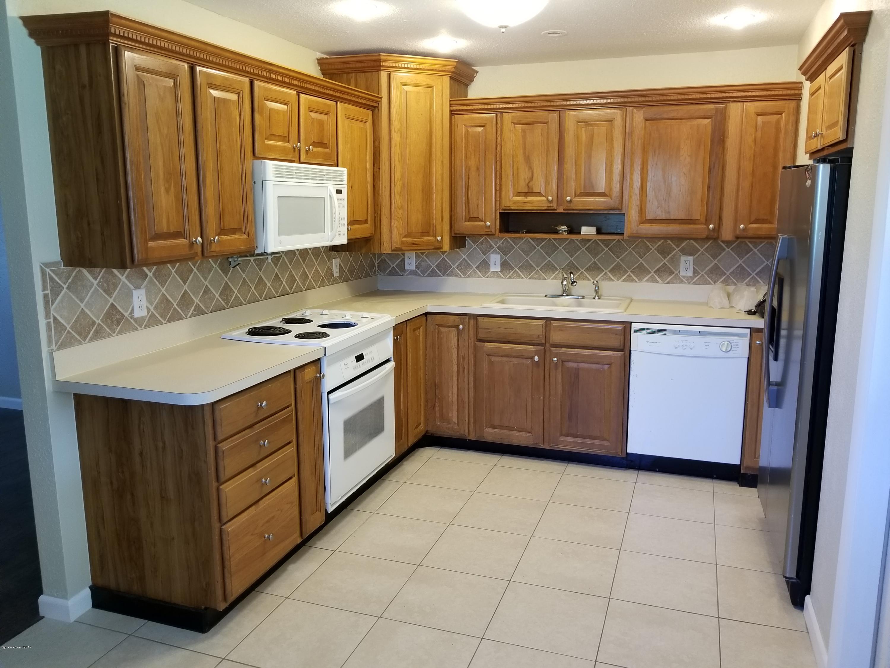 2793 Breeze Ridge Road Melbourne, FL 32935 - Photo 3 of 15 a kitchen with stainless steel appliances granite countertop a stove a sink and a refrigerator with wooden cabinets