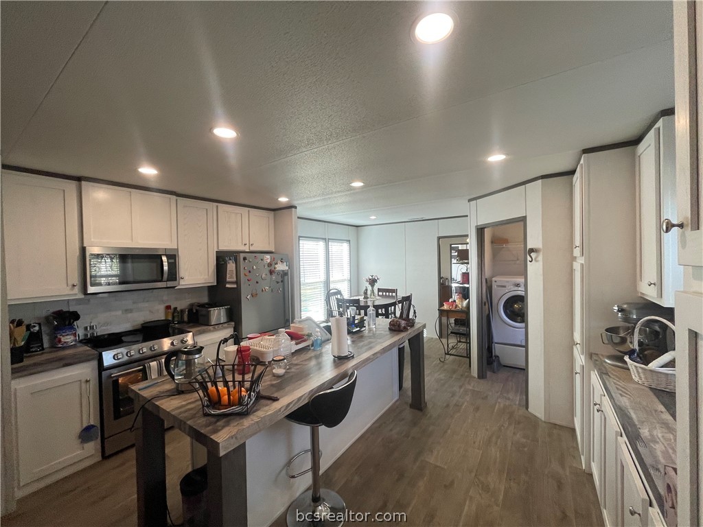 11320 Old Hearne Road Bryan, TX 77807 - Photo 3 of 26 a kitchen with stainless steel appliances kitchen island granite countertop a sink refrigerator and cabinets