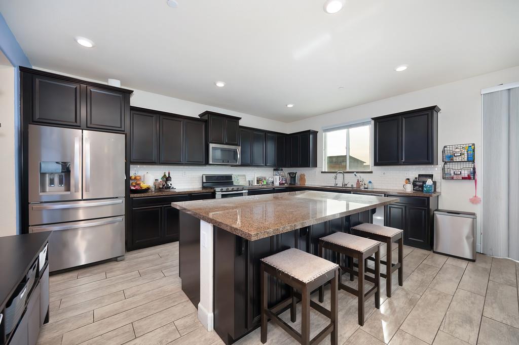 1004 Lavender Street Manteca, CA 95337 - Photo 6 of 35 a kitchen with a refrigerator a microwave a sink and cabinets