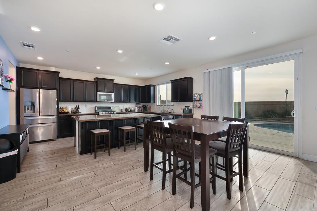 1004 Lavender Street Manteca, CA 95337 - Photo 9 of 35 a kitchen with stainless steel appliances kitchen island granite countertop a table chairs microwave and sink