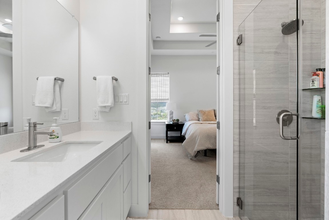 307 Cartwheel Bend Austin, TX 78738 - Photo 23 of 38 a en suite bathroom with a double vanity sink a mirror and shower