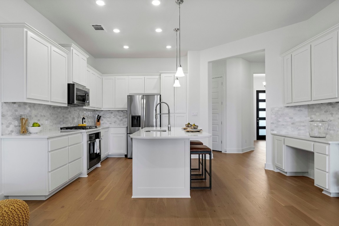 307 Cartwheel Bend Austin, TX 78738 - Photo 6 of 38 a kitchen with stainless steel appliances granite countertop a refrigerator a stove top oven a sink dishwasher and white cabinets with wooden floor